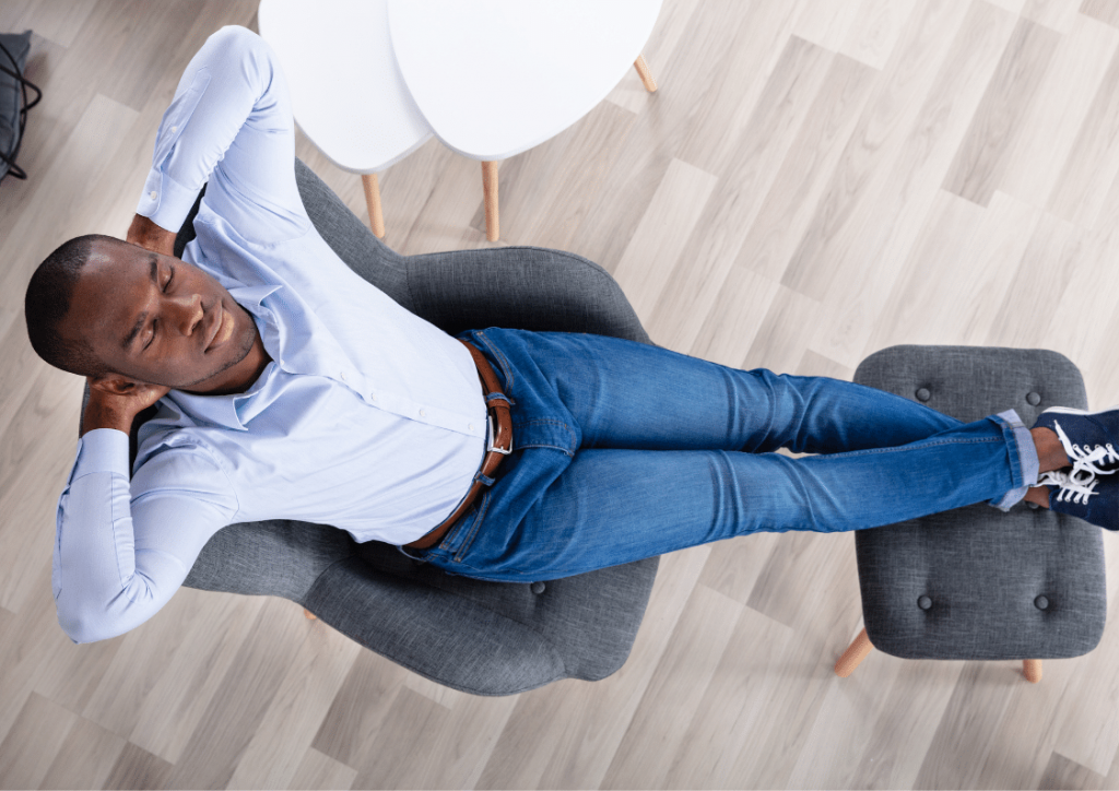 Man sleeping in a grey reclining office chair with matching footstool