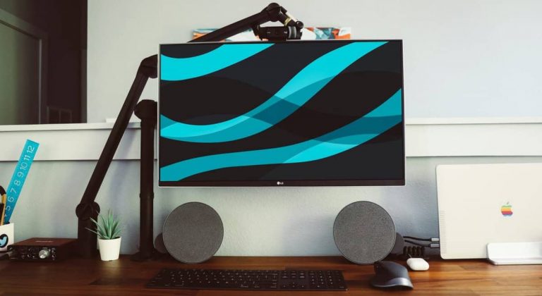 A heavy monitor on a monitor arm above a wooden desk